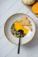 A plate of mashed pumpkin soup on wooden table top view, flat lay. Autumn menu concept photo