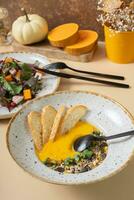 A plate of mashed pumpkin soup and salad. Autumn menu concept photo