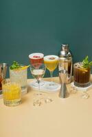 Composition with alcoholic cocktails and bar tools on podiums on colored background. photo