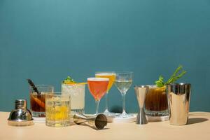 Composition with set of alcoholic cocktails and bar tools on podiums on colored background. Copy space. photo