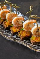 Close up shrimp and mango chutney canapes on dark background. Mini sandwich, catering concept photo