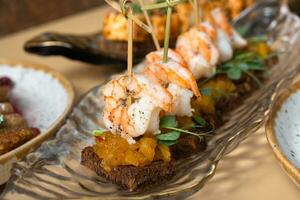 Close up shrimp and mango chutney canapes in glass plate. Mini sandwiches and other dishes photo