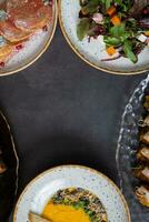 Frame of different dishes in plates on dark background with copy space top view. Delicious autumn dishes photo