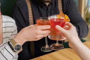 Alcoholic cocktails in hands over a wooden cafeteria table. Party concept photo