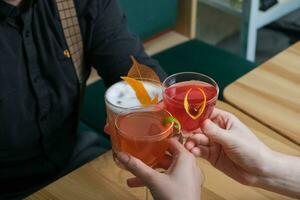 salud con alcohólico cócteles en mano. un noche con amigos en un café foto