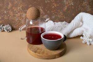 Cup and teapot with cranberry tea with winter decorating. Warm drink still life photo
