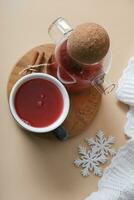 Flat lay cup and teapot with cranberry tea and plaid with snowflakes. Cozy autumn warm drink top view photo