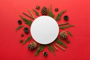 Flat lay Christmas composition. Round Paper blank, pine tree branches, christmas decorations on Colored background. Top view, copy space for text photo