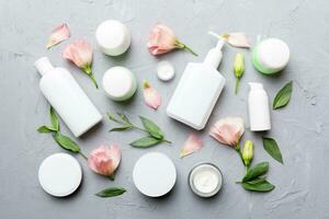 Composition with cosmetic products and beautiful roses on cement background. Flat lay photo
