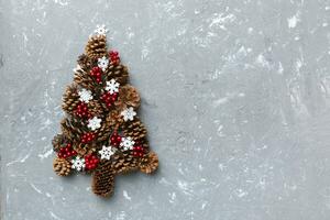 Christmas tree made from natural cones on colored background, view from above. New Year minimal concept with copy space photo