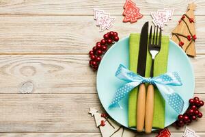 Top view of plate, fork and knife served on Christmas decorated wooden background. New Year Eve concept with copy space photo