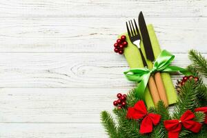 Top view of christmas decorations on wooden background. Fork and knife on napkin tied up with ribbon and empty space for your design. New year pattern concept photo
