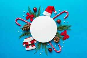 Flat lay Christmas composition. Round Paper blank, pine tree branches, christmas decorations on Colored background. Top view, copy space for text photo