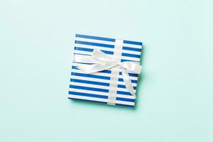 Gift box with white bow for Christmas or New Year day on blue background, top view with copy space photo