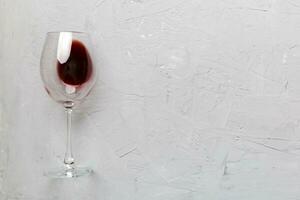 uno lentes de rojo vino a vino saboreo. concepto de rojo vino en de colores antecedentes. parte superior vista, plano laico diseño foto