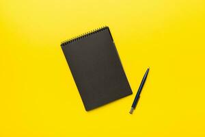 school notebook on a colored background, spiral black notepad on a table Top view photo