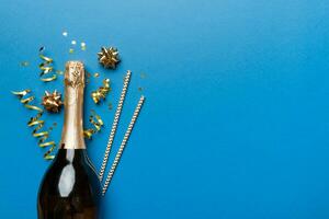 bottle of champagne with glasses and colorful confetti on colored background. top view flay lay photo