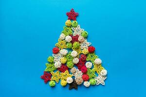 Christmas tree made from colored handmade ball decoration on colored background, view from above. New Year minimal concept with copy space photo