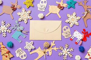 Festive decorations and toys on purple background. Top view of craft envelope. Merry Christmas concept photo