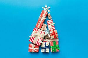 Christmas tree made of beautifuly wrapped presents on colored background, view from above. New Year gift box minimal concept with copy space photo