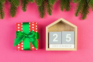 Top view of wooden calendar, gift box and fir tree on colorful background. The twenty fifth of December. Christmas time with copy space photo