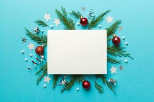 Flat lay Christmas composition. square Paper blank, pine tree branches, christmas decorations on Colored background. Top view, copy space for text photo