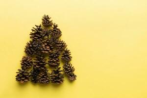 Christmas tree made from natural cones on colored background, view from above. New Year minimal concept with copy space photo