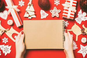 Top view of female hand making some notes in noteebok on colorful background. New Year decorations and toys. Christmas time concept photo