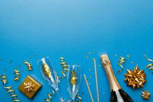 Bottle of champagne with colored glitter, confetti and gift box space for text on colorfull background, top view. Hilarious, christmas and birthday celebration photo