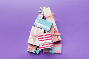 Christmas tree made of beautifuly wrapped presents on colored background, view from above. New Year gift box minimal concept with copy space photo