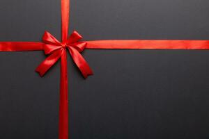 Top view of Red ribbon rolled and red bow isolated on colored background. Flat lay with copy space photo