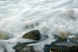 turbulencia de agua de mar y rocas en la costa foto