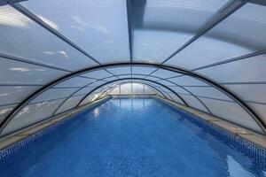 Picture of a swimming pool with a closed semicircular cover made of metal and glass photo