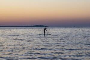 Picture of a single standup paddler in the evening in front of the setting sun photo