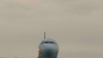 Airplane flies to land overhead, sunset. Bottom view, passenger airliner descending, approaching video