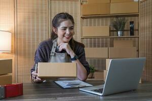 Startup small business entrepreneur SME, asian woman packing cloth in box. Portrait young Asian small business owner home office, online sell marketing delivery, SME e-commerce telemarketing concept photo