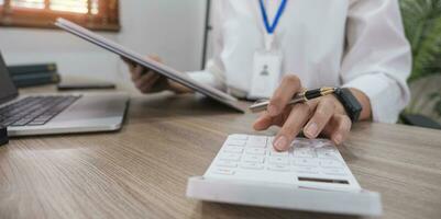 Close up Business woman using calculator and laptop for do math finance on wooden desk in office and business working background, tax, accounting, statistics and analytic research concept photo
