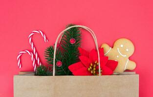 Christmas gifts in paper eco bag on on a red background. Flatlay composition. Holiday gift shopping concept. Top view. Close-up. photo