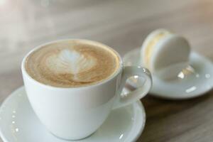 un taza de aromático capuchino y macaron en un mesa a el cafetería. selectivo enfocar. foto