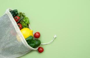 Vegetables and fruits in eco bag on the green background. Zero waste concept. Copy space. Copy space. Selective focus. photo