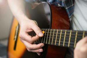 A young man with mediator playing guitar. Close-up. Selective focus. photo