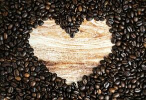 Heart made of coffee beans on wooden background. World coffee day. Copy space. Top view. Selective focus. photo