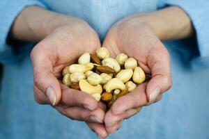 Close-up of woman's hands holding a handful a mixed of nuts. Healthy food concept. Selective focus. photo