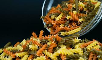 Italian tricolor fusilli paste on the dark background. Close-up. Selective focus. photo