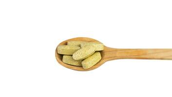 Natural vitamins and supplements in a wooden spoon isolated on white background. Top view. Close-up. photo