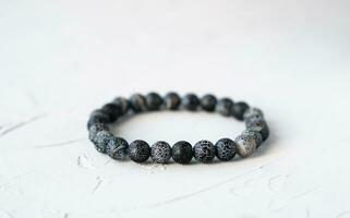 Natural lava stone bracelet on a gray concrete background. Close-up. Copy space. photo