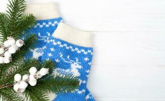 festivo flatlay composición con un abeto sucursales, Navidad decoración y de punto calcetines en un blanco de madera antecedentes. parte superior vista. Copiar espacio. selectivo enfocar. foto