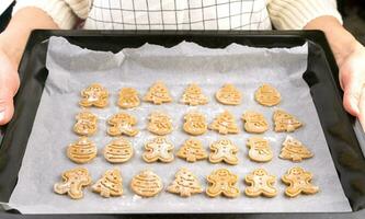 joven mujer participación horneando sábana con Navidad galletas. hecho en casa horneando para Navidad. de cerca. selectivo enfocar. foto