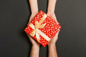 Top view of two people sharing a present on colorful background. Holiday and surprise concept. Copy space photo