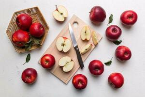 Fresh red apples with green leaves on table. cutting board with knife. Top view photo